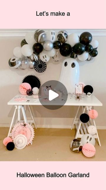 a table with balloons and other decorations on it, including a ghost balloon garland for halloween