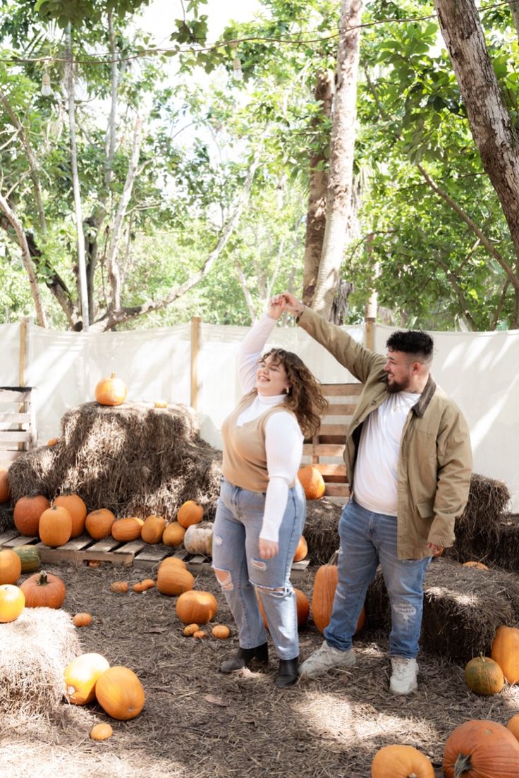 a man and woman standing in front of pumpkins