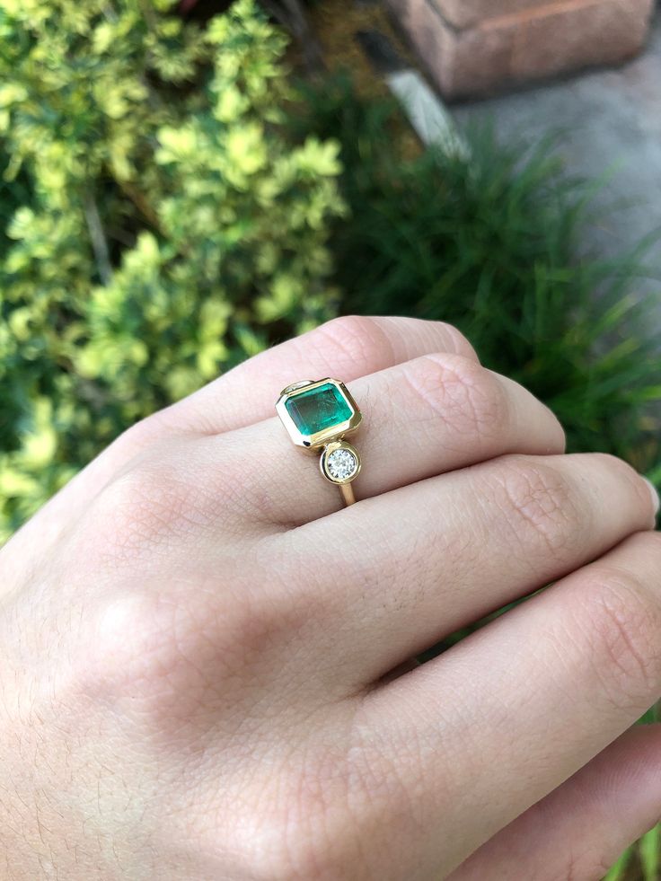 A classic Colombian emerald and diamond three-stone ring. Dexterously crafted in gleaming 14K gold this ring features a natural Colombian emerald-Asscher cut from the famous Muzo mines. Set in a secure bezel setting, this extraordinary emerald has a bright green color and glow. This emerald has very good eye clarity with natural Jardins that occur in all earth-mined emeralds. Brilliant round cut diamonds weigh an outstanding 0.45 total carat weight. Elegantly accenting either side of the emerald Elegant Emerald Cut Three Stone Birthstone Ring, Timeless Emerald Gemstone Wedding Ring, Elegant 14k Stamped Emerald Ring, Green Three Stone Emerald Cut Jewelry, Timeless Green Jewelry With Bezel Setting, Emerald Cut Three Stone Birthstone Ring, Timeless Diamond Emerald Ring With Bezel Setting, 14k Gold Jewelry With Asscher Cut Gemstone, Elegant 14k Gold Asscher Cut Emerald Ring