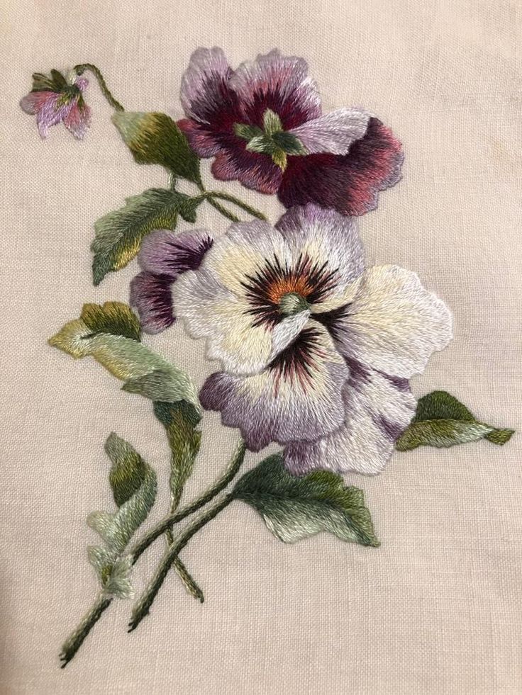 an embroidered piece of cloth with purple flowers on the front and green leaves on the back