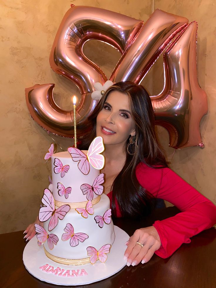 a woman sitting at a table in front of a cake with pink butterflies on it