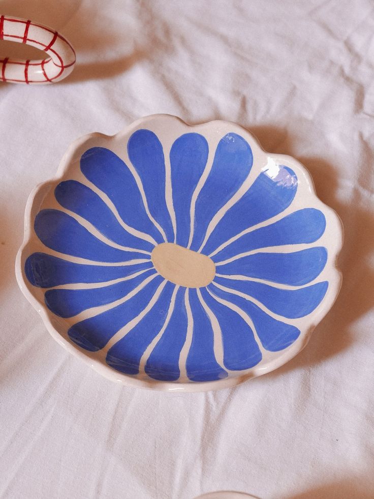 a blue and white bowl sitting on top of a bed next to two red shoes