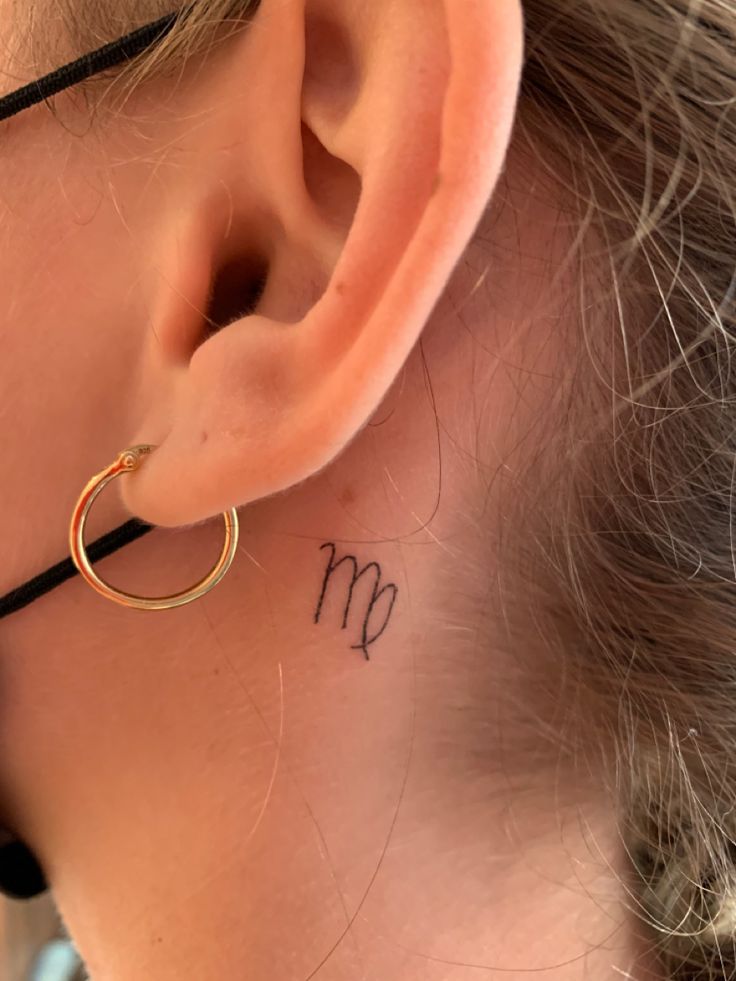 a close up of a person with a small tattoo on their left side behind the ear