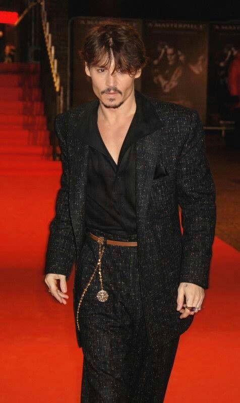 a man in a suit and tie walking down a red carpeted area with his hands in his pockets