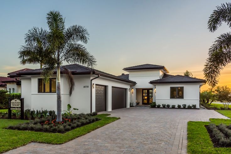 a white house with palm trees in the front yard and landscaping around it at sunset