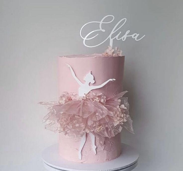 a pink and white cake with a ballerina on top