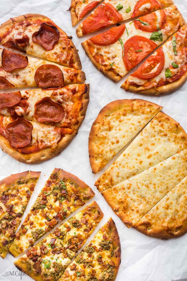 four different types of pizzas on top of white paper with slices missing from them