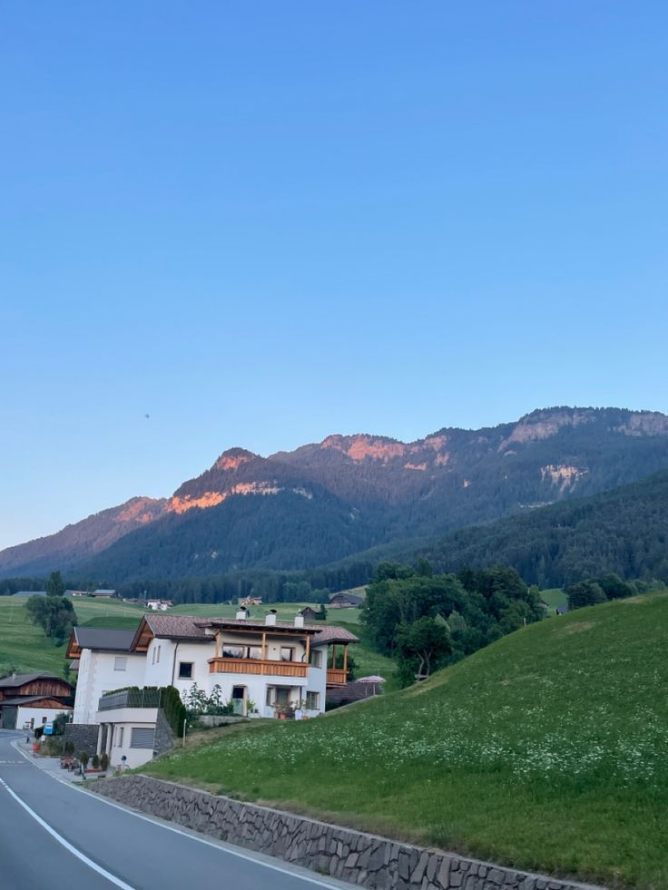 an empty road in the middle of a green valley with mountains in the back ground