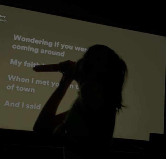 a woman standing in front of a projection screen with her hand up to her face