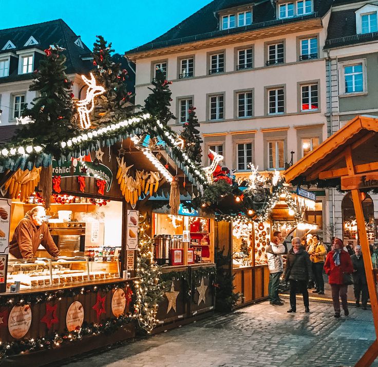 an outdoor market with christmas decorations and lights on it's display stands in front of buildings