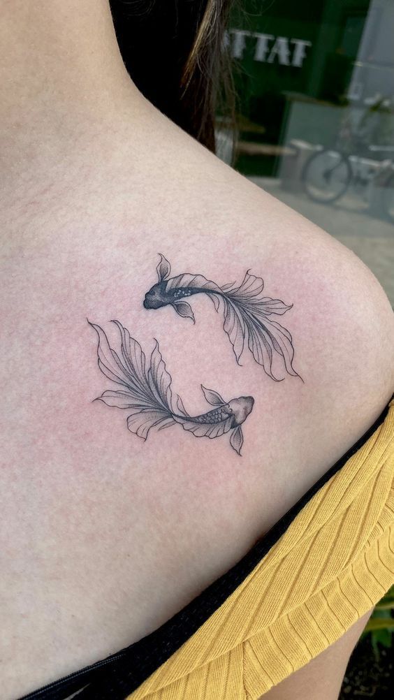 a woman with a tattoo on her shoulder has a fish in the shape of a circle