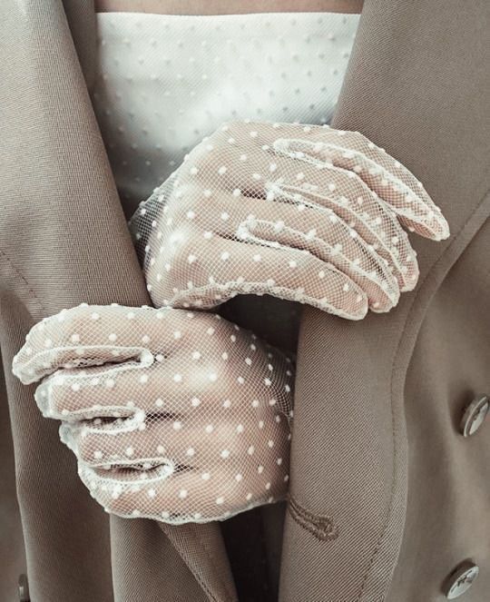 a close up of a person's hands with gloves on their fingers and polka dots