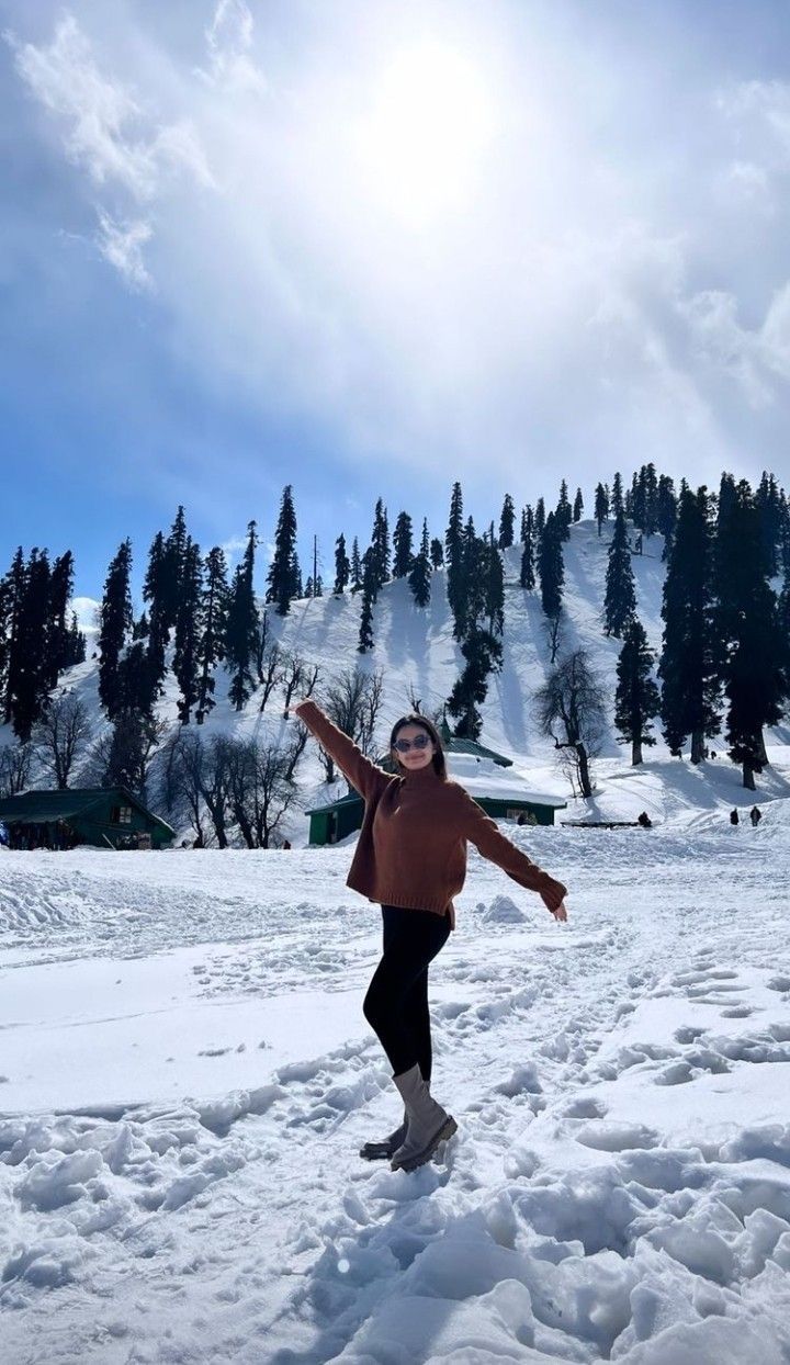 a woman standing in the snow with her arms outstretched