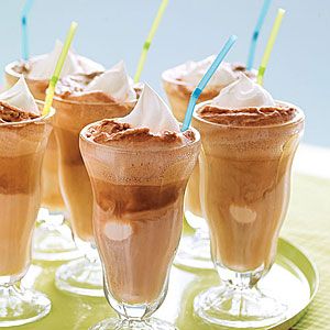 four glasses filled with ice cream and chocolate milkshakes on a green tablecloth