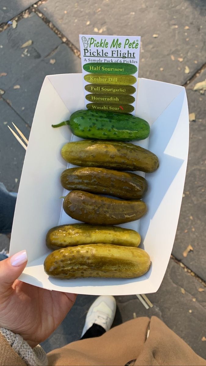 a person holding up a box full of pickles