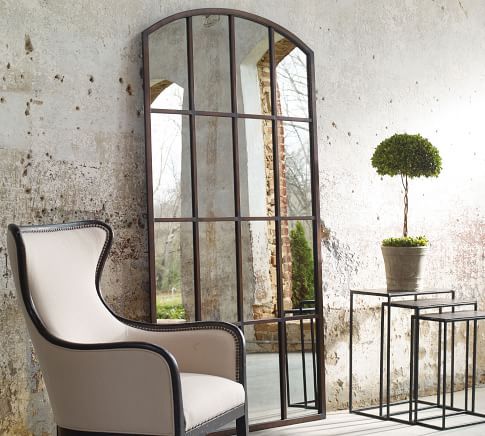 a white chair sitting in front of a mirror next to a table with a potted plant on it