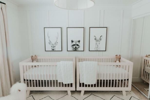 two baby cribs in a white nursery with pictures on the wall above them