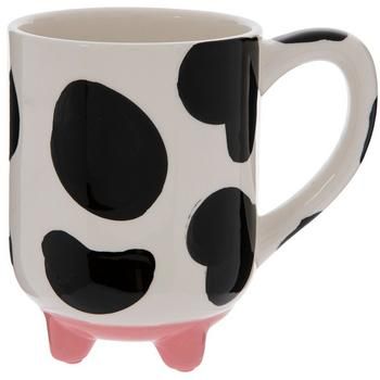 a black and white cow shaped coffee mug with pink feet on the bottom, sitting in front of a white background