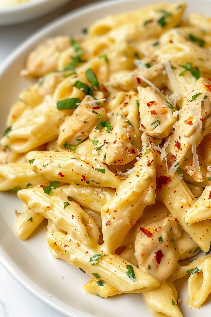 pasta with chicken and parmesan cheese on a white plate, ready to be eaten