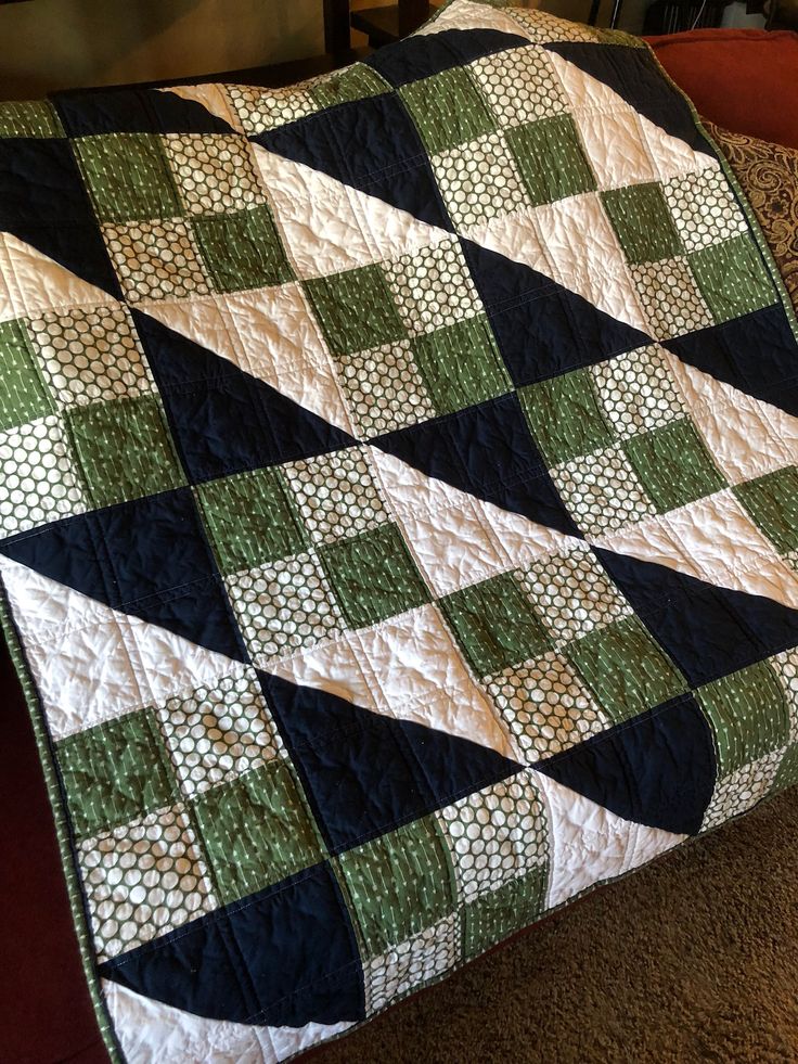 a green and black quilt sitting on top of a couch