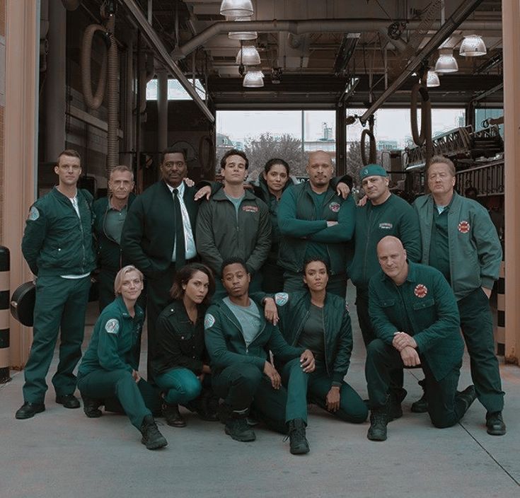 a group of men and women posing for a photo in front of an industrial building