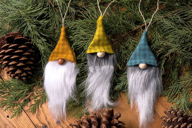 three gnome ornaments hanging from a pine tree