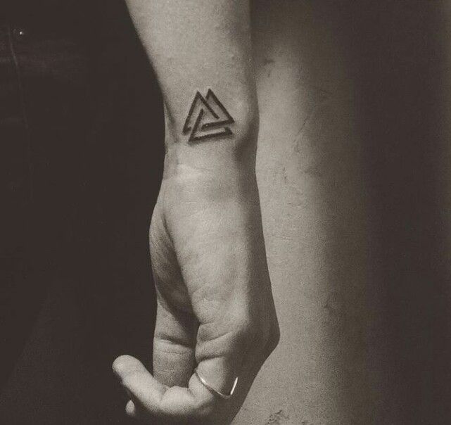 a person with a small triangle tattoo on their hand