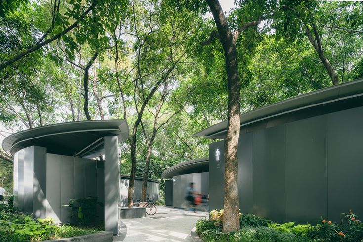 the walkway is lined with trees and bushes, leading up to two circular buildings that are surrounded by greenery