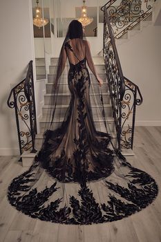 a woman in a black dress is standing at the top of stairs with her back to the camera