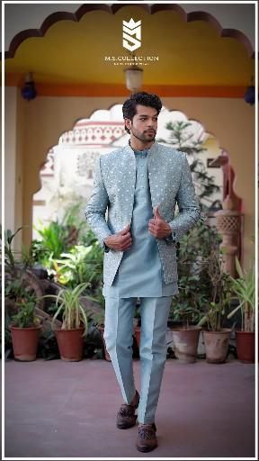 a man in a blue suit and brown shoes walking down a walkway with potted plants behind him