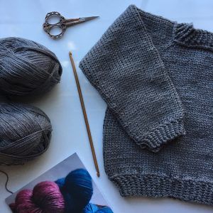 the knitting supplies are laid out on the table to be used for knitted sweaters