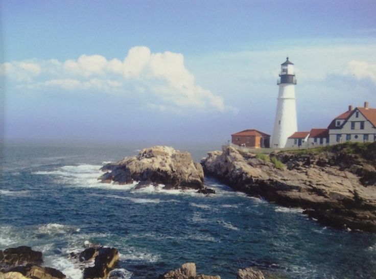 a light house sitting on top of a rocky cliff next to the ocean with waves coming in