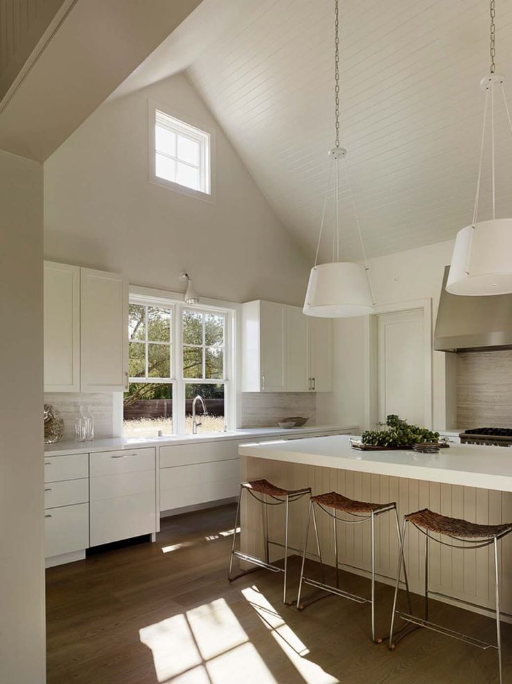 a kitchen with white cabinets and an island in the middle, along with three stools