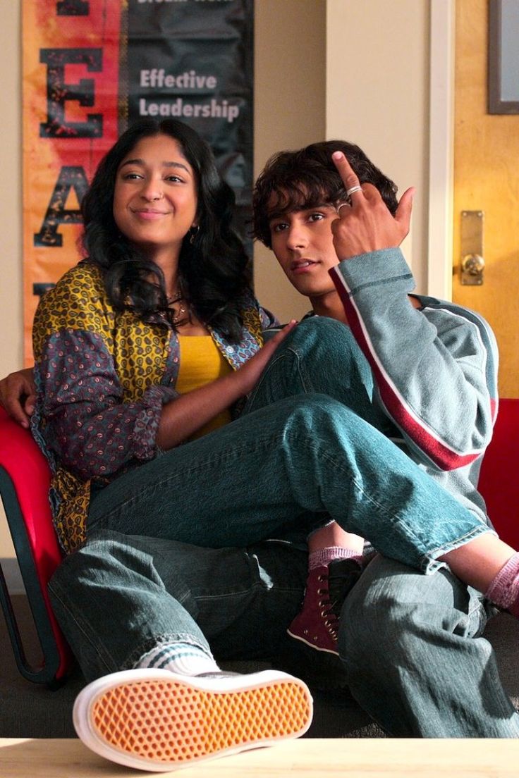 a young man and woman sitting on a red chair in front of a sign that says effective leaders