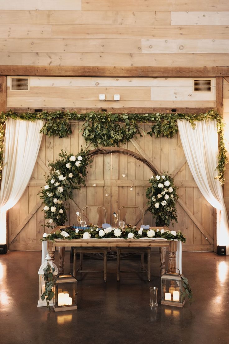 a table with flowers and candles is set up in front of a barn door for a wedding