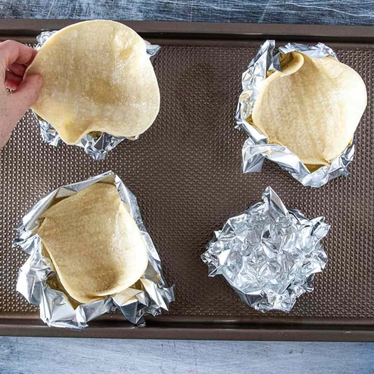 three uncooked pita breads sitting on top of aluminum foil