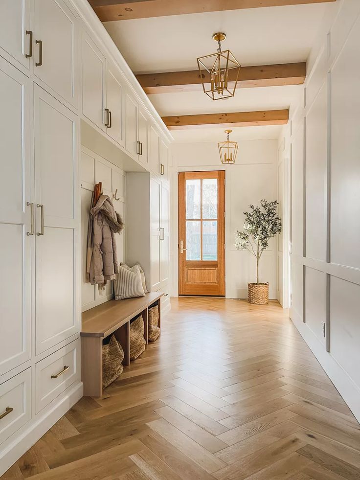 a hallway with white cabinets and wooden floors