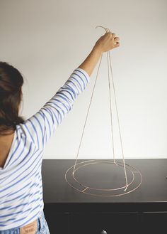 a woman is holding strings in front of a black table with an object on it