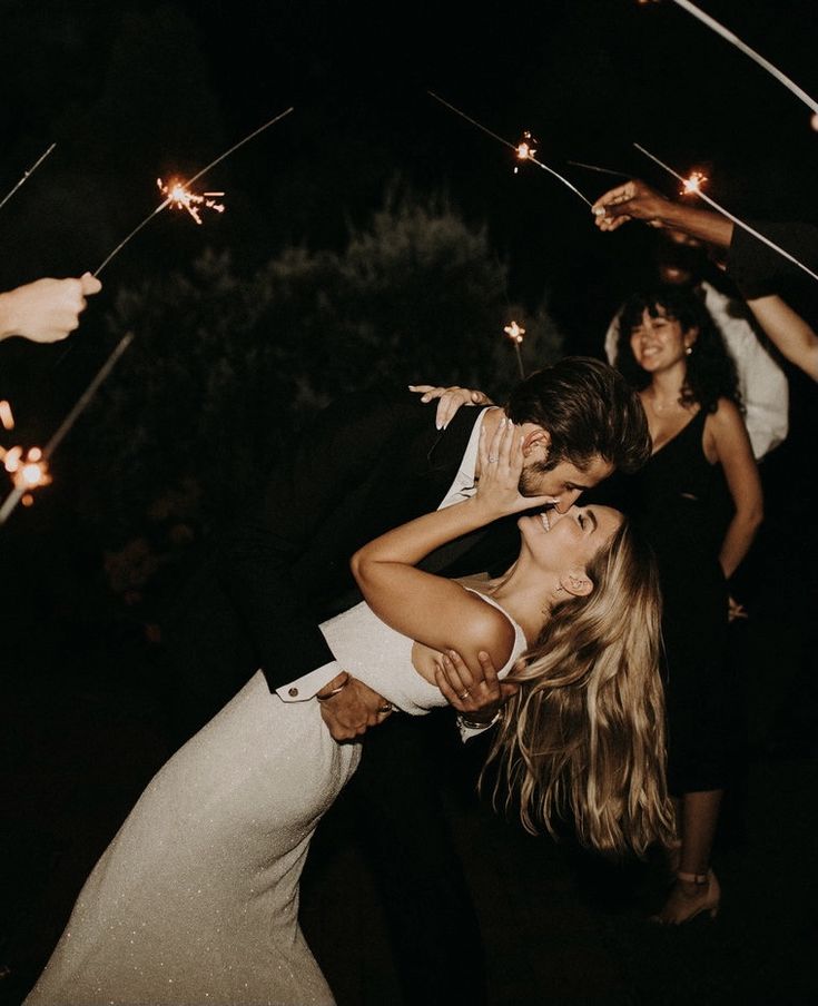 a man and woman dancing with sparklers in the air