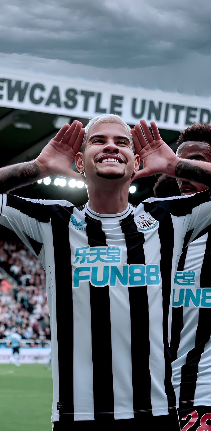 two men in black and white shirts standing on a soccer field with their hands up