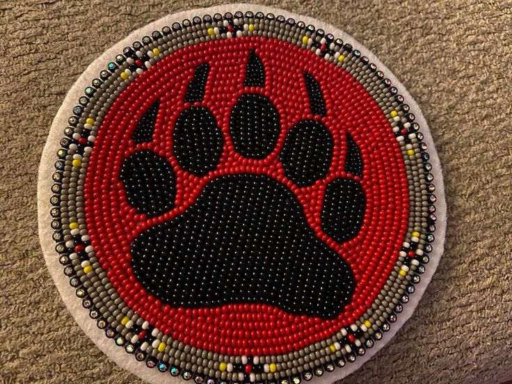 a red and black beaded patch with a paw on it