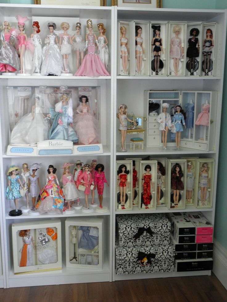 a white bookcase filled with lots of barbie dolls