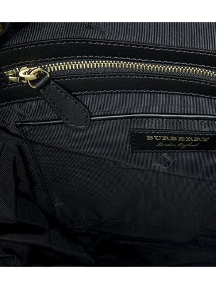 The Burberry Large 'Rucksack' Backpack, crafted with sustainable nylon and leather trims, measures 15.5 x 15.4 x 9.5 inches. Its black color and sophisticated design make it a statement piece. It features a drawstring fastening, top handle, adjustable shoulder straps, padded back, and multiple pockets for storage. Made in Italy, it is finished with beige buckle detailing, gold-toned hardware, and a logo plaque in gold-tone letters. Dimensions: 15.5 x 15.4 x 9.5 inches; Color: Black. Sustainable Designer Black Backpack With Top Carry Handle, Luxury Backpack With Leather Handles, Designer Travel Tote Backpack, Luxury Backpack With Leather Top Handle, Luxury Top Handle Backpack With Leather Handles, Luxury Backpack With Top Handle And Leather Handles, Luxury Travel Backpack With Top Handle, Luxury Coated Canvas Leather Backpack With Zipper, Designer Black Backpack With Leather Trim