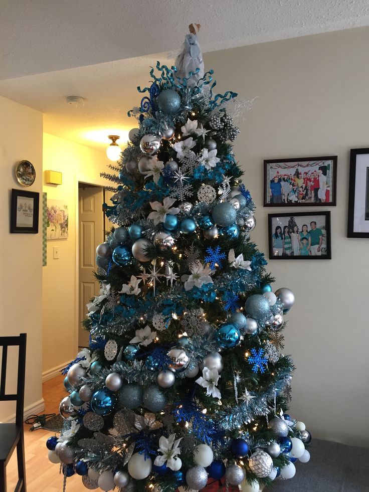 a blue christmas tree with silver and white ornaments