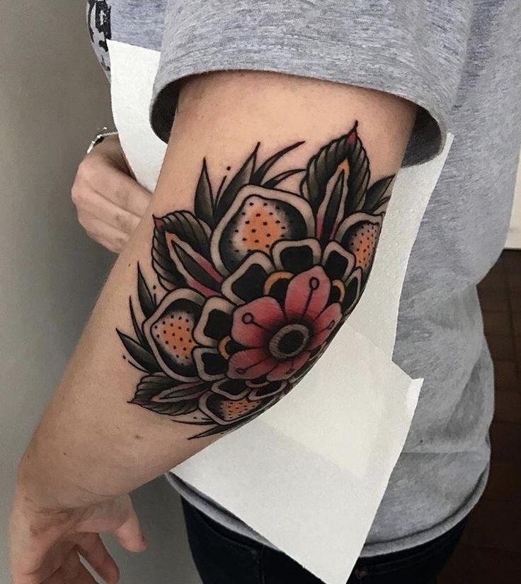 a woman's arm with flowers on it, and an orange flower in the center