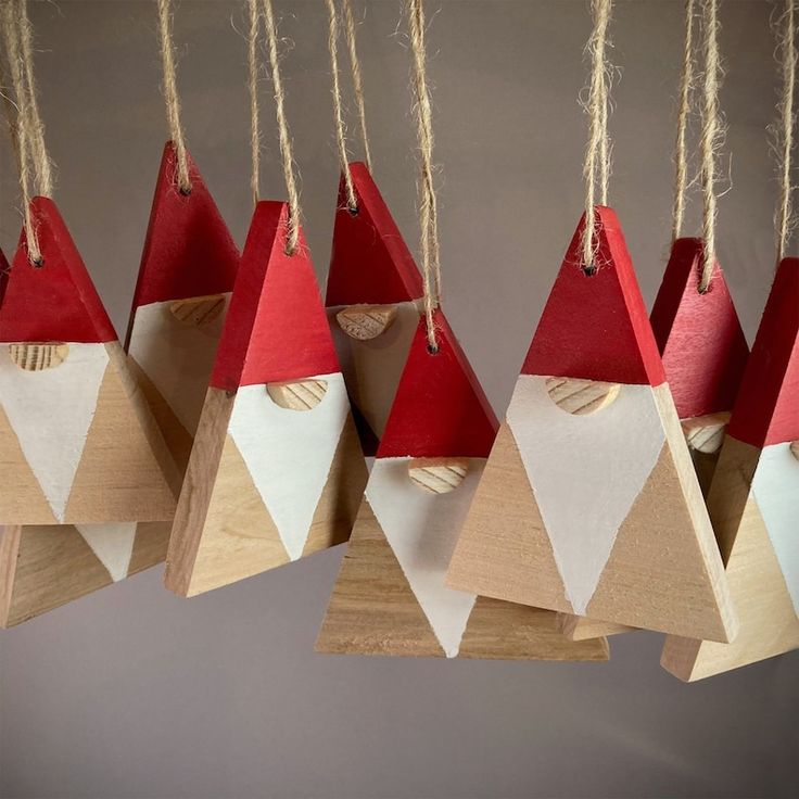 several wooden ornaments hanging from strings in the shape of santa's hats