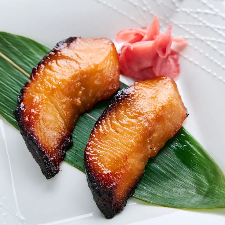 two pieces of pineapple sitting on top of a green leaf next to a pink flower