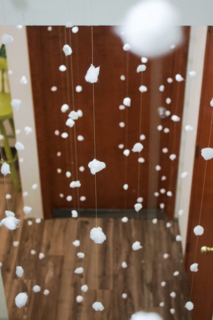 a room filled with lots of white balls hanging from it's ceiling next to a wooden door