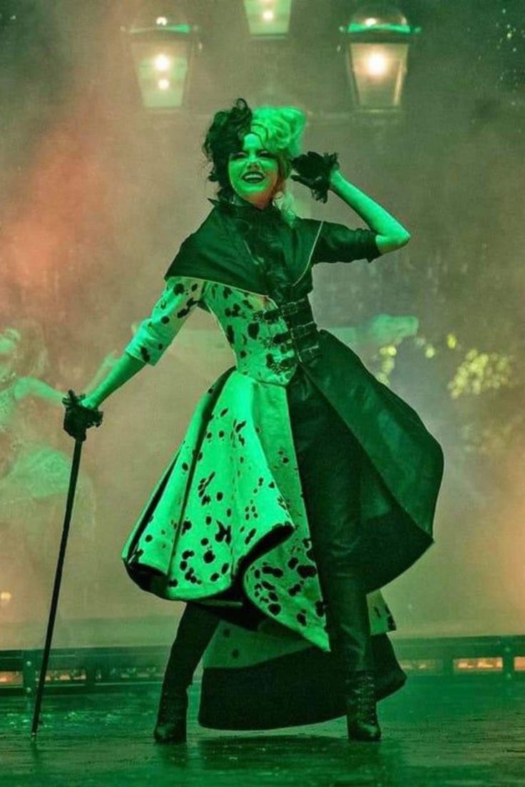 a woman with green hair and makeup is performing in front of some people on stage