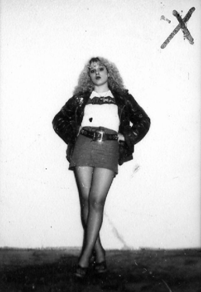 an old black and white photo of a woman in short skirt standing with her hands on her hips